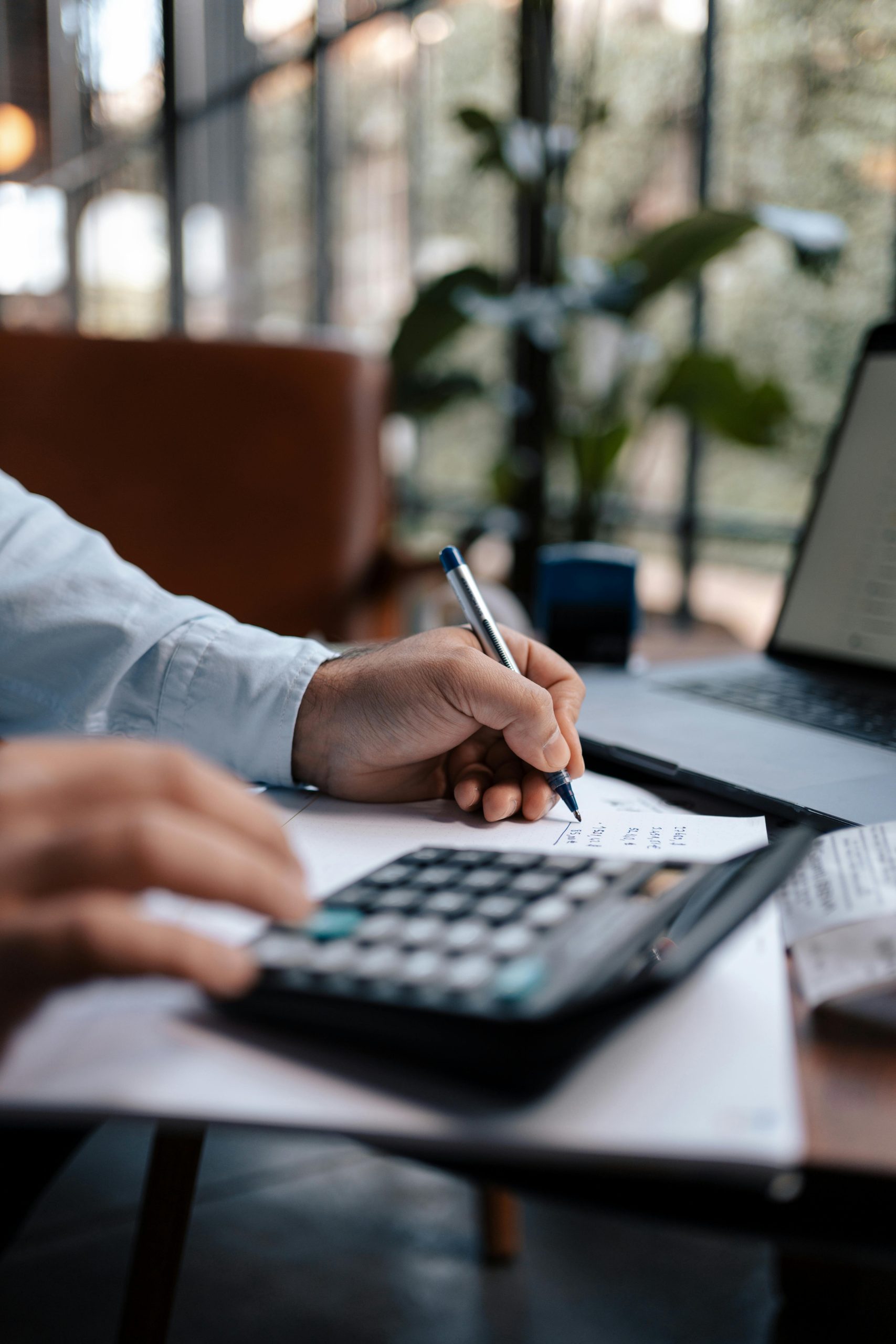 Accountant using calculator at desk to calculate taxes